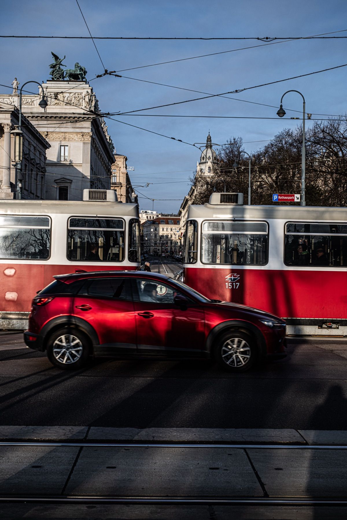 Red trams and a car on a city street